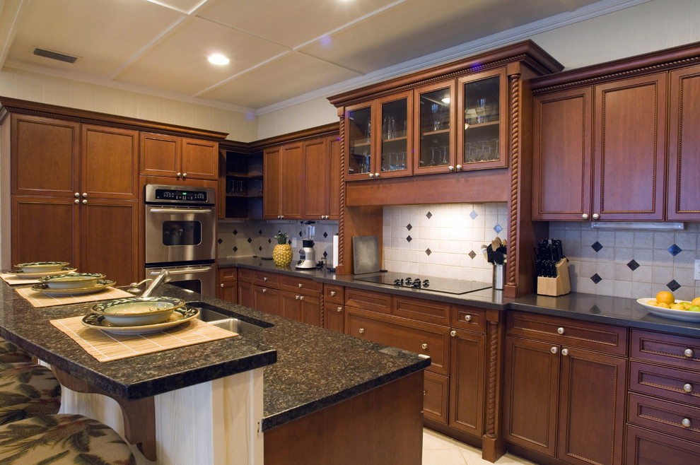 Immagine di una grande cucina stile marinaro con ante con riquadro incassato, ante in legno bruno, top in granito e elettrodomestici da incasso
