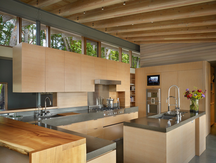 Example of a trendy l-shaped concrete floor open concept kitchen design in Seattle with an undermount sink, flat-panel cabinets, light wood cabinets, concrete countertops, gray backsplash, paneled appliances and an island
