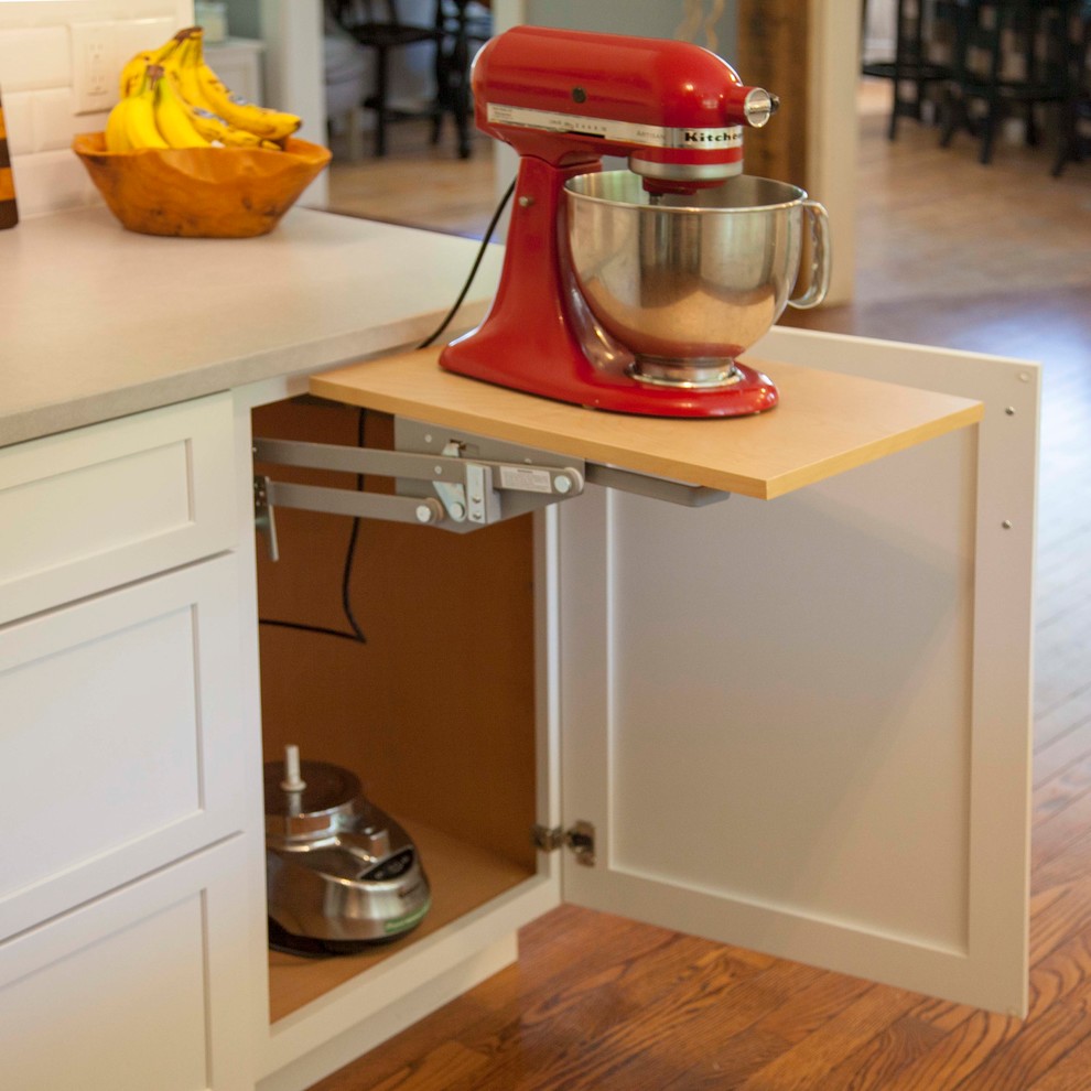 Example of a mid-sized farmhouse l-shaped medium tone wood floor and red floor eat-in kitchen design in New York with a farmhouse sink, shaker cabinets, white cabinets, quartz countertops, white backsplash, subway tile backsplash, stainless steel appliances, a peninsula and gray countertops