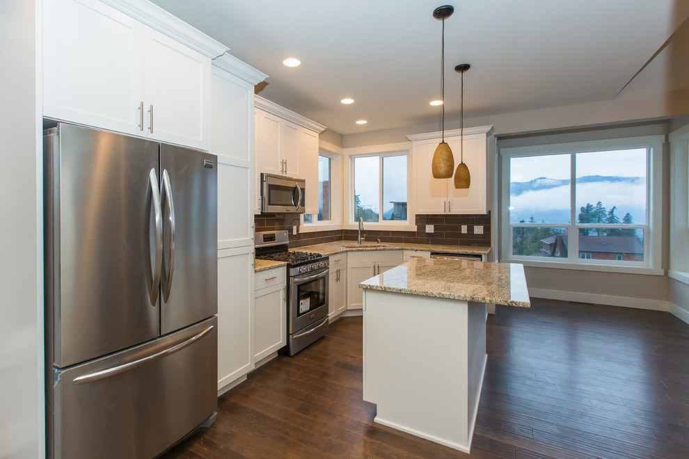 Inspiration for a small timeless u-shaped dark wood floor open concept kitchen remodel in Portland with a drop-in sink, shaker cabinets, white cabinets, granite countertops, black backsplash, subway tile backsplash, stainless steel appliances and an island