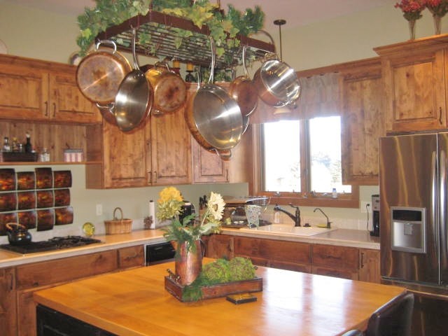 Rustik inredning av ett mellanstort kök, med en dubbel diskho, luckor med upphöjd panel, skåp i mellenmörkt trä, träbänkskiva, svart stänkskydd, stänkskydd i stenkakel och rostfria vitvaror