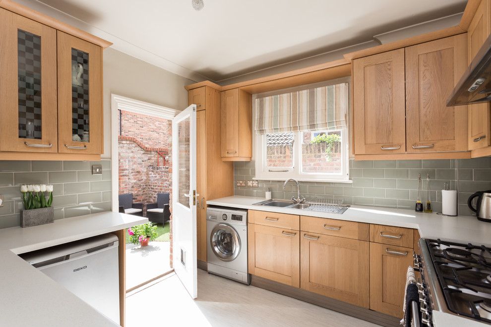 Inspiration for a small traditional u-shaped enclosed kitchen in Other with a double-bowl sink, shaker cabinets, medium wood cabinets, laminate countertops, white splashback, metro tiled splashback, stainless steel appliances, lino flooring and no island.