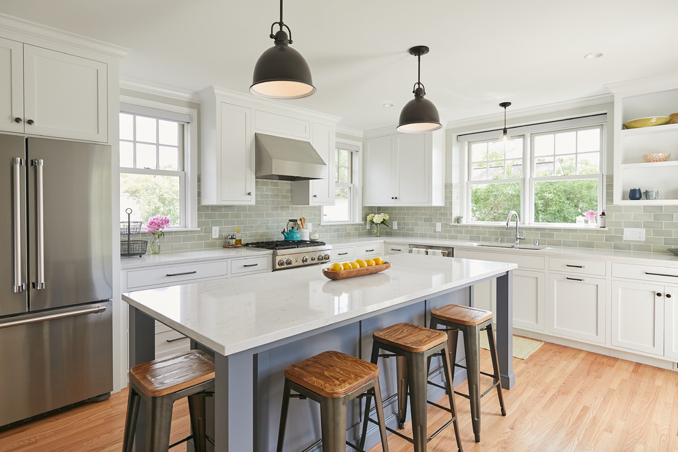 Inspiration for a transitional l-shaped medium tone wood floor and brown floor enclosed kitchen remodel in Minneapolis with a double-bowl sink, shaker cabinets, white cabinets, quartz countertops, green backsplash, porcelain backsplash, stainless steel appliances, an island and white countertops