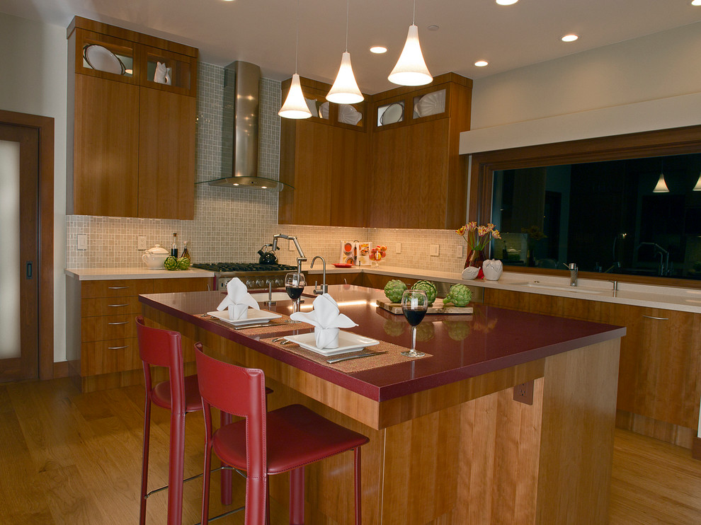 Foto på ett mellanstort funkis kök, med en enkel diskho, släta luckor, skåp i mellenmörkt trä, beige stänkskydd, rostfria vitvaror, ljust trägolv och en köksö