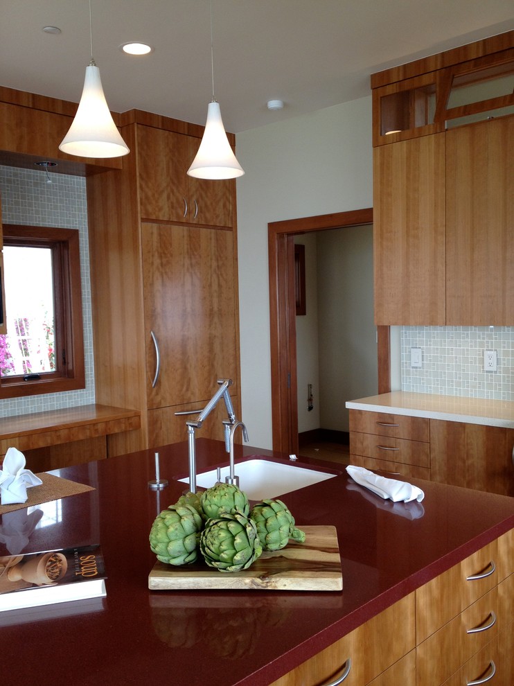 Cette photo montre une cuisine américaine tendance en U et bois brun avec un placard à porte plane, une crédence beige, un électroménager en acier inoxydable et îlot.
