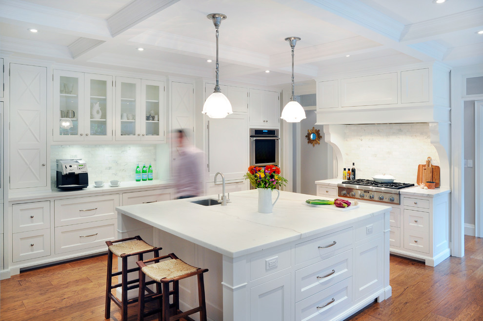 Example of a huge classic l-shaped medium tone wood floor kitchen design in Toronto with an undermount sink, shaker cabinets, white cabinets, marble countertops, white backsplash, paneled appliances and an island