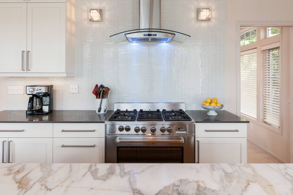 Bild på ett mellanstort funkis kök, med en dubbel diskho, skåp i shakerstil, gula skåp, marmorbänkskiva, vitt stänkskydd, stänkskydd i glaskakel, rostfria vitvaror, ljust trägolv och en köksö