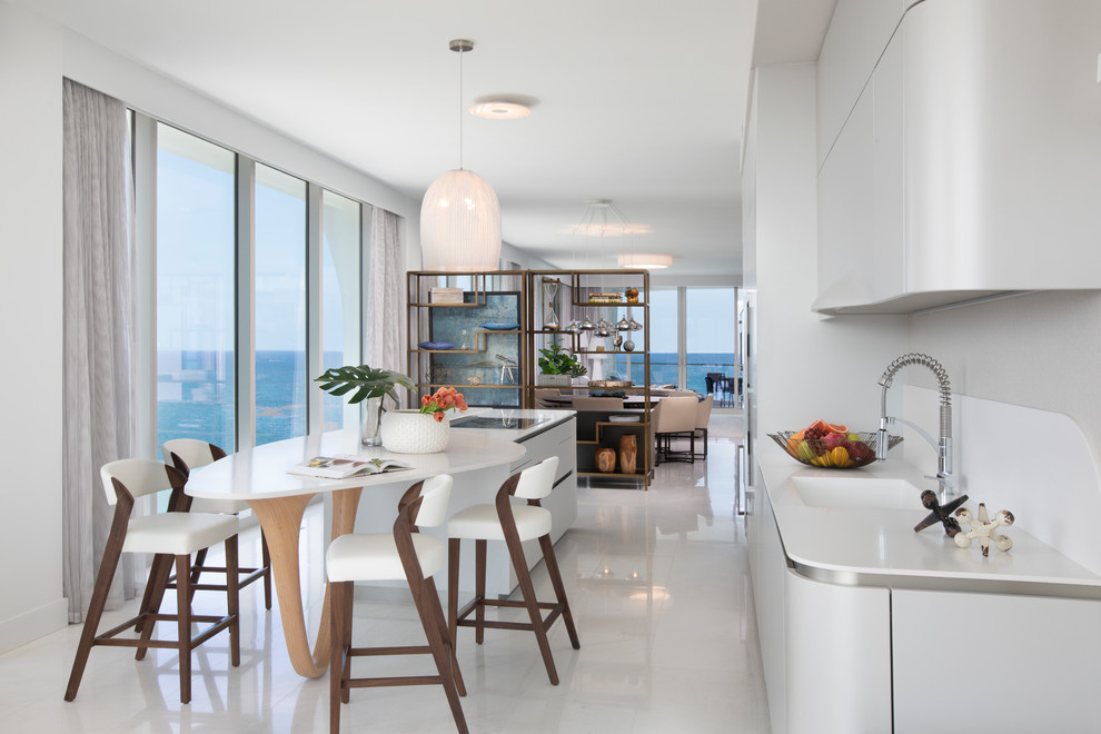 Immagine di una cucina minimal con lavello integrato, ante lisce, ante bianche, paraspruzzi bianco, elettrodomestici da incasso, pavimento bianco e top bianco