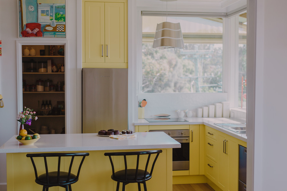 Küche mit gelben Schränken und Kücheninsel in Hobart