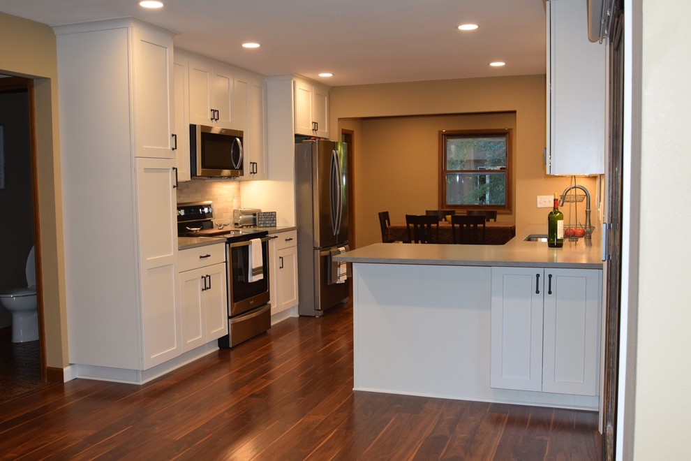 Example of a mid-sized classic u-shaped laminate floor and brown floor eat-in kitchen design in Other with a single-bowl sink, shaker cabinets, white cabinets, quartzite countertops, beige backsplash, marble backsplash, stainless steel appliances, a peninsula and gray countertops
