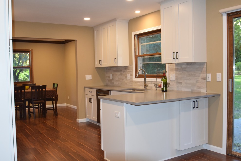 Mid-sized elegant u-shaped laminate floor and brown floor eat-in kitchen photo in Other with a single-bowl sink, shaker cabinets, white cabinets, quartzite countertops, beige backsplash, marble backsplash, stainless steel appliances, a peninsula and gray countertops
