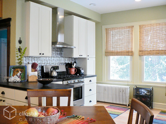 Eat-in kitchen - mid-sized transitional u-shaped light wood floor eat-in kitchen idea in Philadelphia with shaker cabinets, white cabinets, solid surface countertops, metallic backsplash, metal backsplash and stainless steel appliances