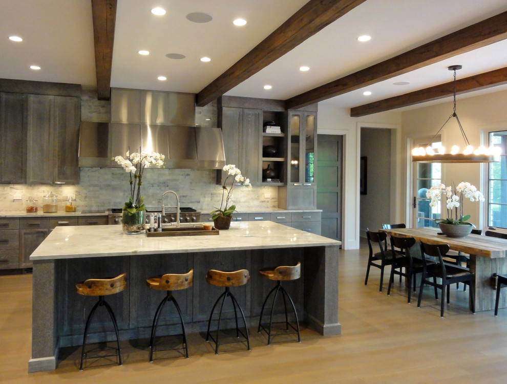 Inspiration for a large transitional l-shaped light wood floor kitchen remodel in Chicago with an undermount sink, raised-panel cabinets, distressed cabinets, granite countertops, beige backsplash, stone tile backsplash, stainless steel appliances and an island
