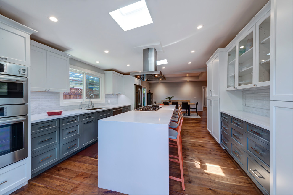 Inspiration for a large contemporary galley kitchen/diner in San Francisco with stainless steel appliances, dark hardwood flooring, an island, beige floors, white worktops, a submerged sink, shaker cabinets, white cabinets, engineered stone countertops and white splashback.