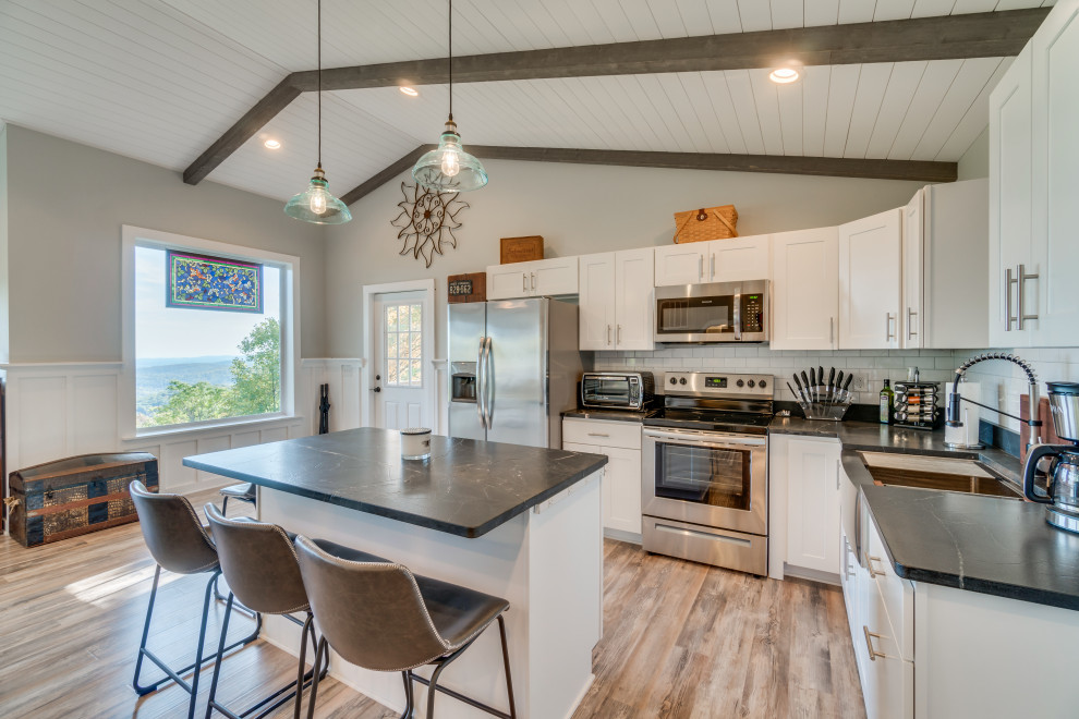 Small eclectic l-shaped light wood floor and shiplap ceiling eat-in kitchen photo in DC Metro with a farmhouse sink, shaker cabinets, white cabinets, granite countertops, white backsplash, ceramic backsplash, stainless steel appliances, an island and black countertops