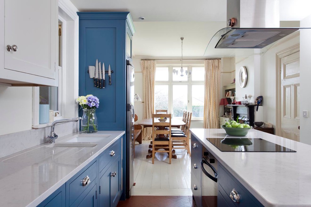Modelo de cocina comedor costera con fregadero bajoencimera, armarios estilo shaker, puertas de armario azules, encimera de mármol y una isla