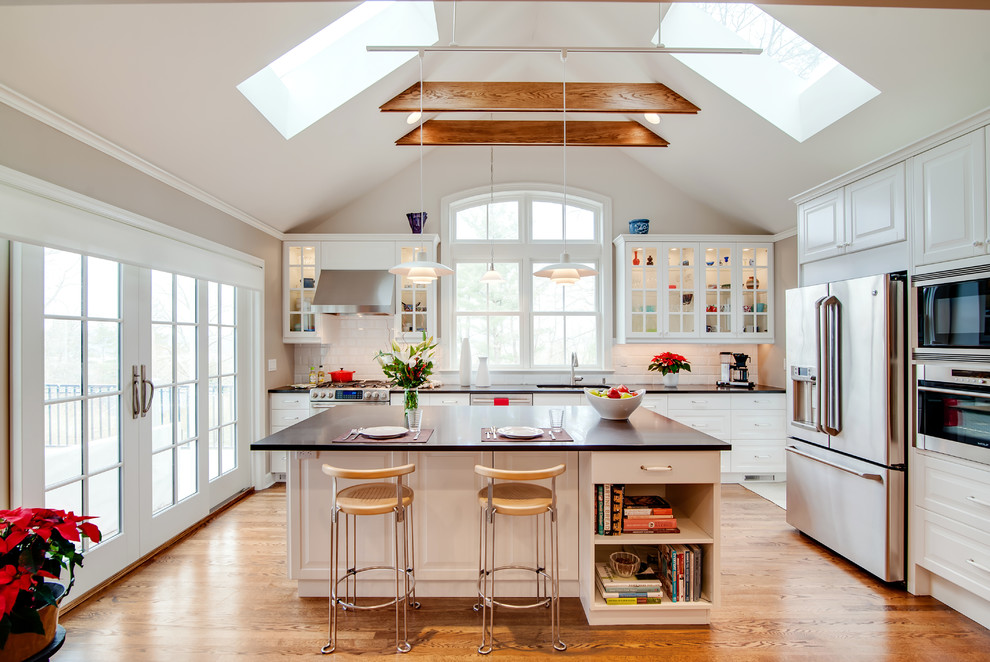 Eat-in kitchen - mid-sized traditional single-wall medium tone wood floor and beige floor eat-in kitchen idea in New York with an undermount sink, raised-panel cabinets, white cabinets, white backsplash, stainless steel appliances, an island, quartz countertops and porcelain backsplash