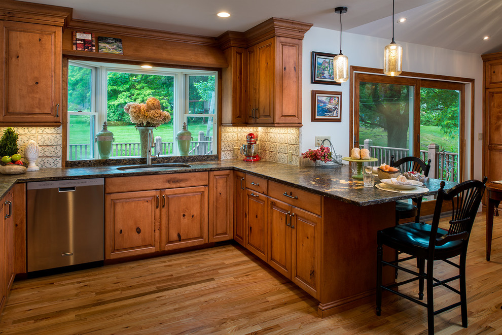 Example of a mountain style u-shaped medium tone wood floor eat-in kitchen design in New York with an undermount sink, raised-panel cabinets, medium tone wood cabinets and stainless steel appliances