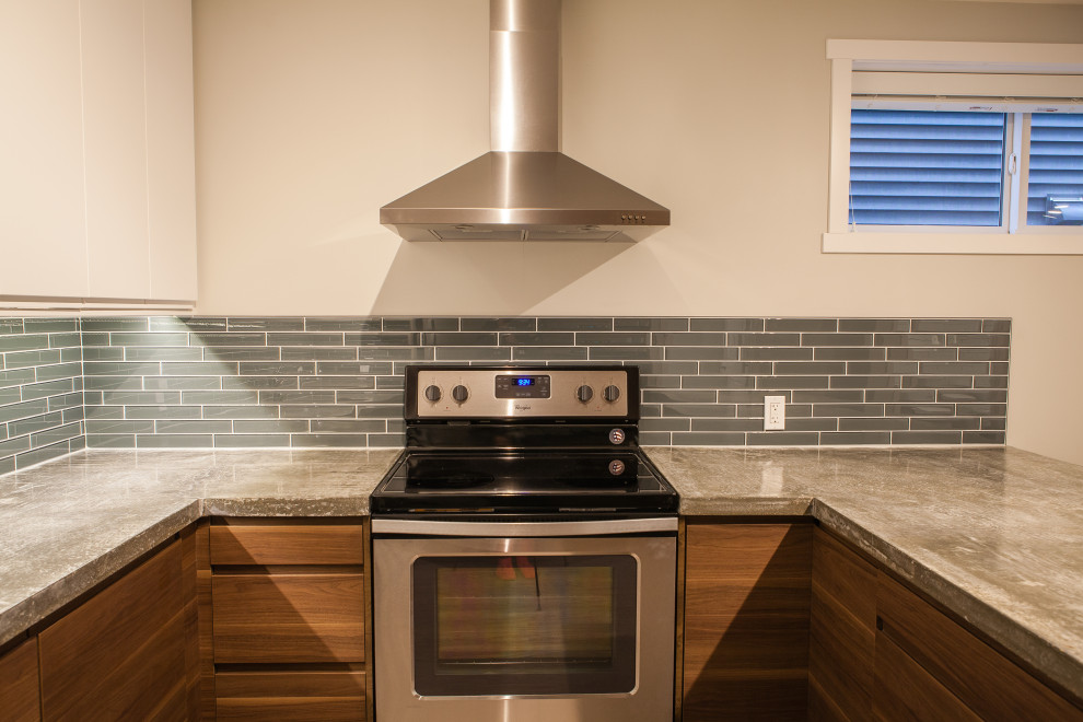 Idéer för att renovera ett avskilt, mellanstort funkis grå grått u-kök, med en undermonterad diskho, släta luckor, bruna skåp, bänkskiva i betong, blått stänkskydd, stänkskydd i glaskakel, rostfria vitvaror och en halv köksö