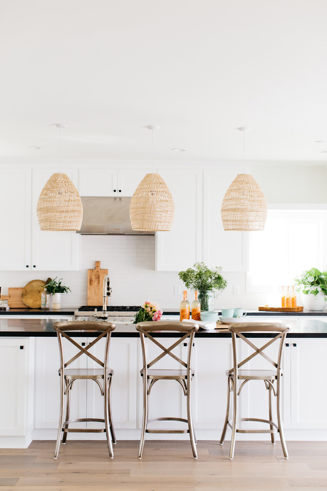 Zweizeilige Maritime Küche mit Schrankfronten im Shaker-Stil, Küchenrückwand in Weiß, braunem Holzboden, Kücheninsel und braunem Boden in San Diego
