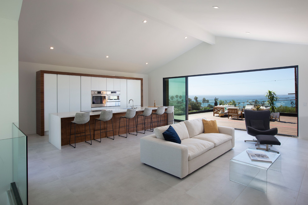 This is an example of a contemporary galley open plan kitchen in San Diego with a submerged sink, flat-panel cabinets, white cabinets, stainless steel appliances, an island, grey floors and white worktops.