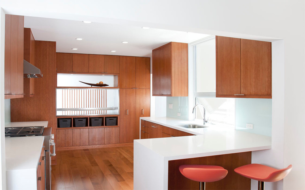 Пример оригинального дизайна: кухня в стиле модернизм с плоскими фасадами, фасадами цвета дерева среднего тона, синим фартуком, барной стойкой и окном