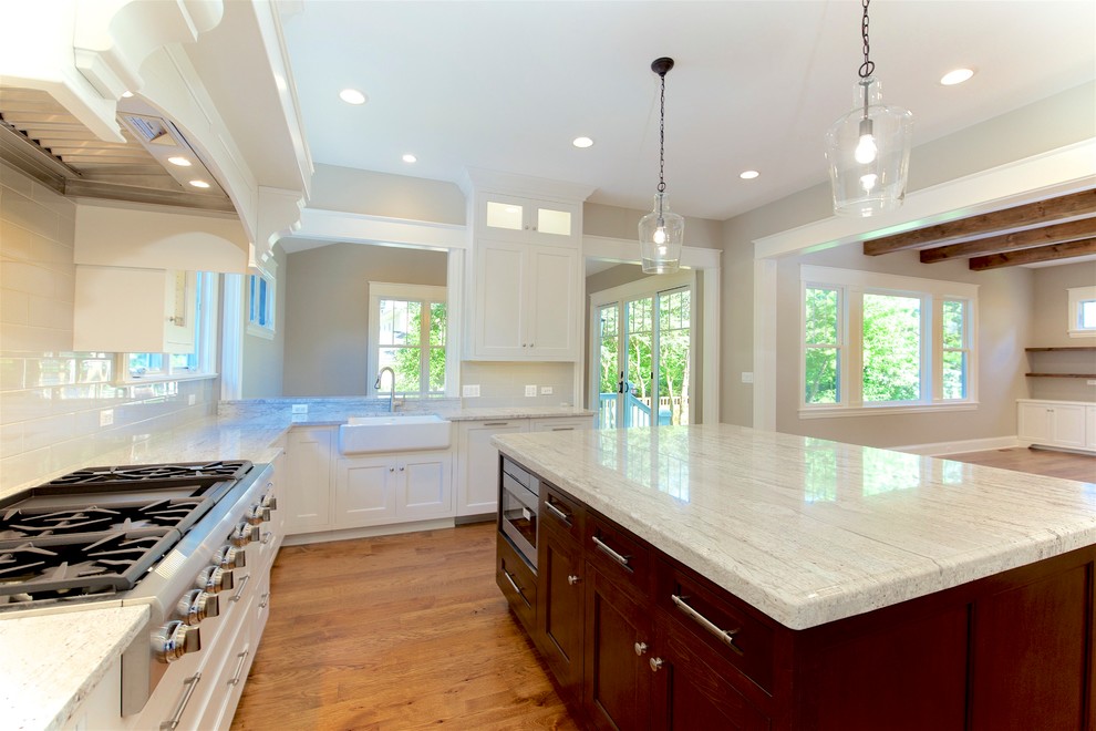 Large elegant u-shaped light wood floor and brown floor open concept kitchen photo in Chicago with a farmhouse sink, recessed-panel cabinets, white cabinets, granite countertops, gray backsplash, subway tile backsplash, paneled appliances and an island