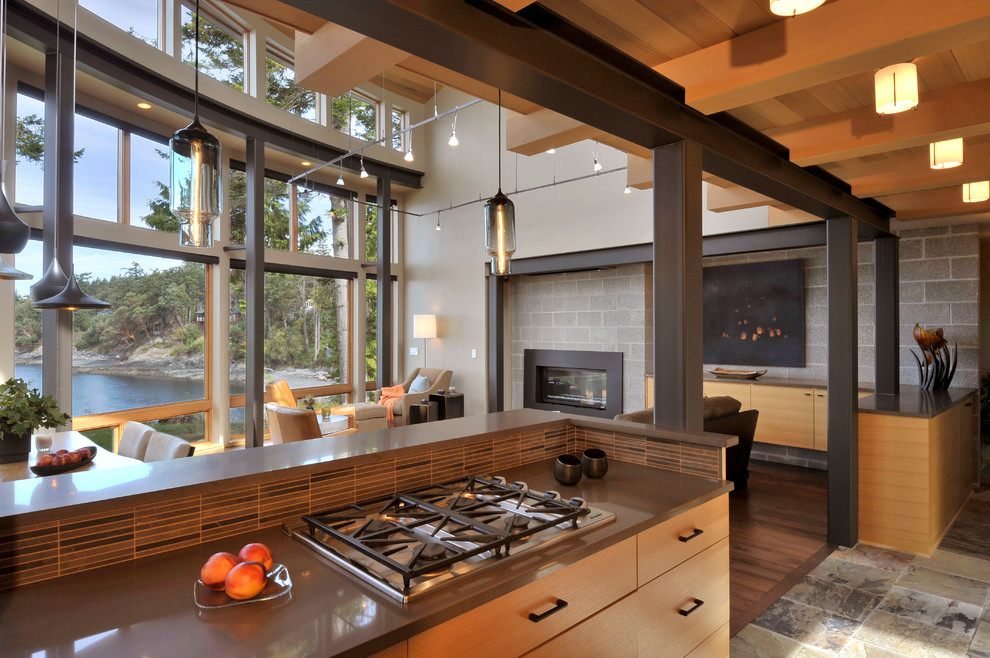 Réalisation d'une cuisine ouverte design en bois clair avec un placard à porte plane et une crédence en carreau briquette.