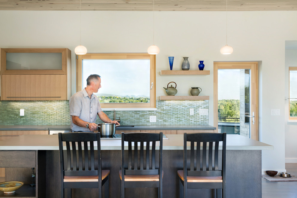 Идея дизайна: параллельная кухня в современном стиле с монолитной мойкой, плоскими фасадами, светлыми деревянными фасадами, зеленым фартуком и островом