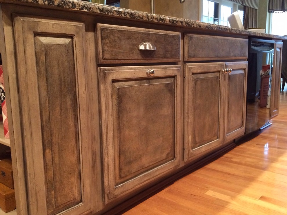 Eat-in kitchen - large craftsman l-shaped light wood floor and brown floor eat-in kitchen idea in Cincinnati with raised-panel cabinets, dark wood cabinets, an undermount sink, granite countertops, stainless steel appliances and an island