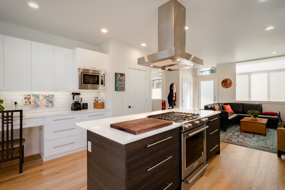 Example of a mid-sized trendy u-shaped medium tone wood floor and brown floor open concept kitchen design in Seattle with an undermount sink, flat-panel cabinets, dark wood cabinets, quartz countertops, white backsplash, porcelain backsplash, stainless steel appliances and an island