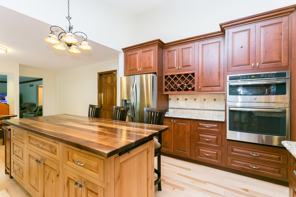 Large transitional l-shaped light wood floor eat-in kitchen photo in St Louis with medium tone wood cabinets, wood countertops, stainless steel appliances, an island, beige backsplash, an undermount sink, raised-panel cabinets and terra-cotta backsplash