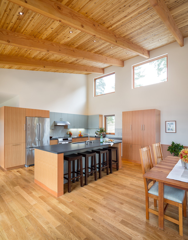 Exempel på ett mellanstort modernt kök, med en enkel diskho, släta luckor, skåp i ljust trä, bänkskiva i koppar, blått stänkskydd, stänkskydd i cementkakel, rostfria vitvaror, mellanmörkt trägolv och en köksö