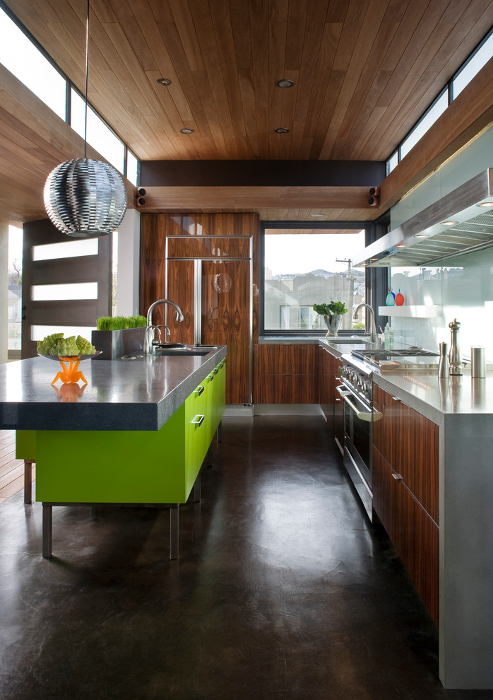 サンフランシスコにあるコンテンポラリースタイルのおしゃれなキッチン (コンクリートカウンター、パネルと同色の調理設備、フラットパネル扉のキャビネット、ガラス板のキッチンパネル、濃色木目調キャビネット) の写真