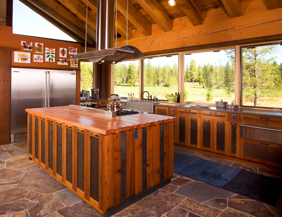 Aménagement d'une cuisine montagne en L et bois brun avec un évier de ferme, un plan de travail en bois et un électroménager en acier inoxydable.