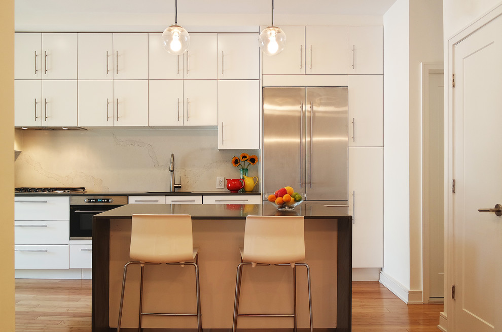 Moderne Küche mit flächenbündigen Schrankfronten, weißen Schränken, Küchengeräten aus Edelstahl, braunem Holzboden und Kücheninsel in New York