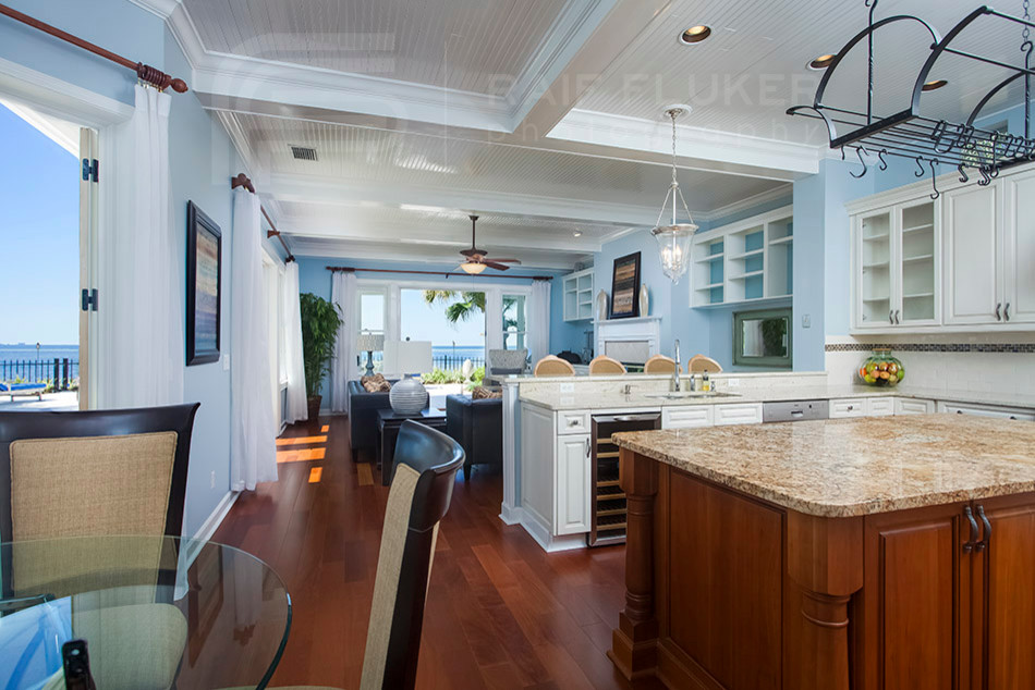 Offene Küche in U-Form mit weißen Schränken, braunem Holzboden und Kücheninsel in Tampa