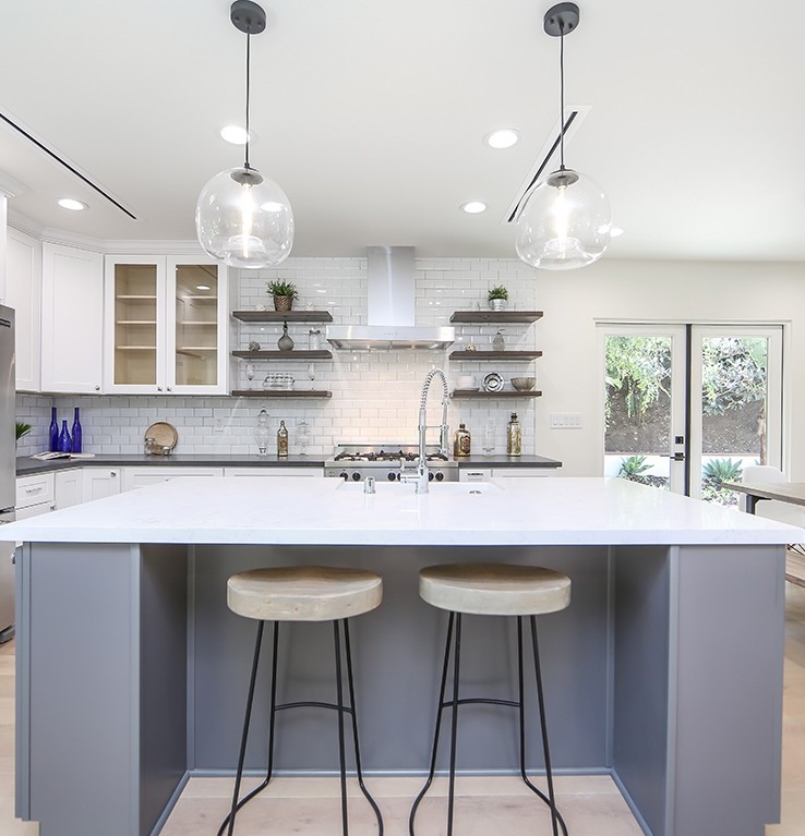 Open concept kitchen - mid-sized coastal l-shaped light wood floor open concept kitchen idea in Los Angeles with a farmhouse sink, shaker cabinets, white cabinets, marble countertops, white backsplash, subway tile backsplash, stainless steel appliances and an island