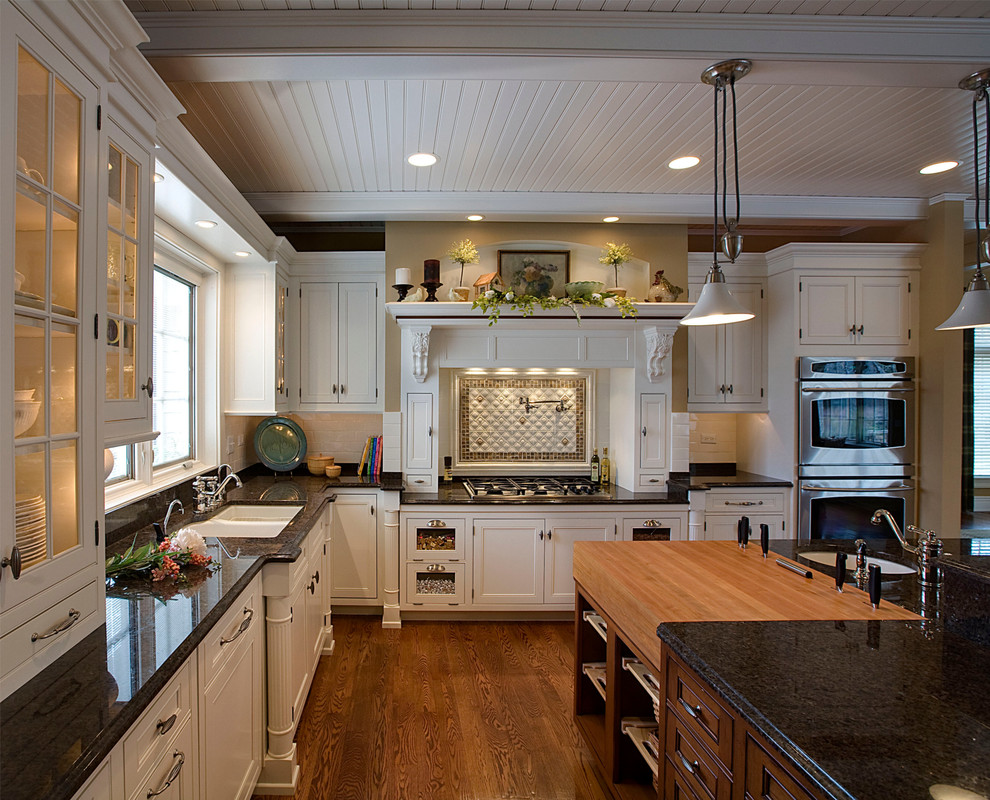 Kitchen - mid-sized traditional l-shaped medium tone wood floor and brown floor kitchen idea in Chicago with an undermount sink, beaded inset cabinets, white cabinets, granite countertops, white backsplash, subway tile backsplash, stainless steel appliances and an island
