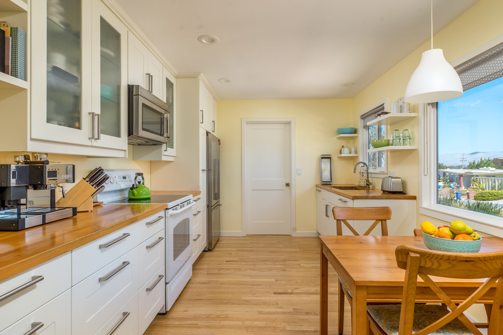 Zweizeilige, Kleine Retro Küche mit Waschbecken, Schrankfronten im Shaker-Stil, weißen Schränken, Arbeitsplatte aus Holz und braunem Holzboden in San Luis Obispo