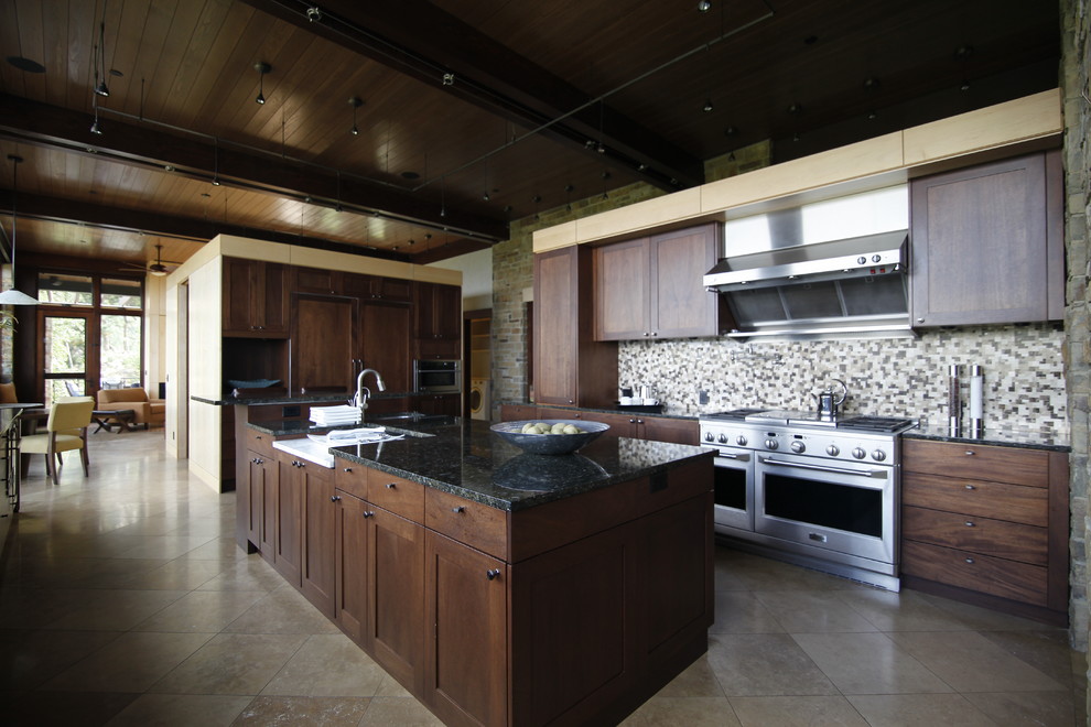 Idéer för ett stort klassiskt svart linjärt kök och matrum, med en nedsänkt diskho, släta luckor, skåp i mörkt trä, granitbänkskiva, beige stänkskydd, stänkskydd i keramik, rostfria vitvaror, travertin golv, en köksö och beiget golv
