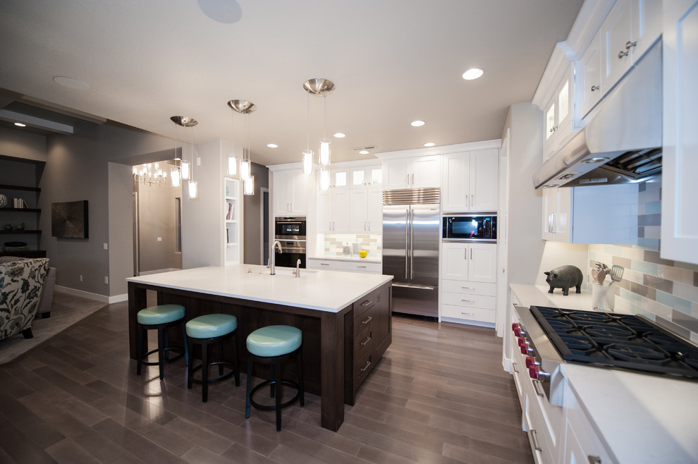 This is an example of a large contemporary l-shaped open plan kitchen in Salt Lake City with a submerged sink, shaker cabinets, white cabinets, soapstone worktops, multi-coloured splashback, porcelain splashback, stainless steel appliances, dark hardwood flooring, an island and brown floors.