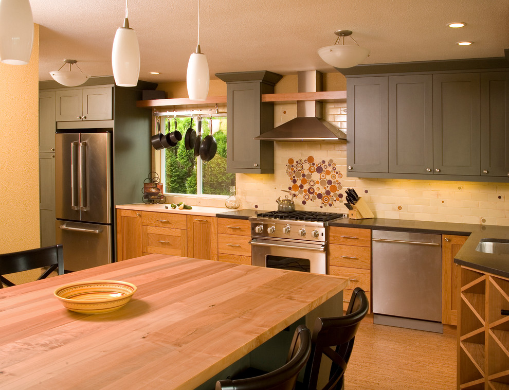 Diseño de cocina clásica con encimera de madera, armarios estilo shaker, puertas de armario grises, salpicadero beige y electrodomésticos de acero inoxidable