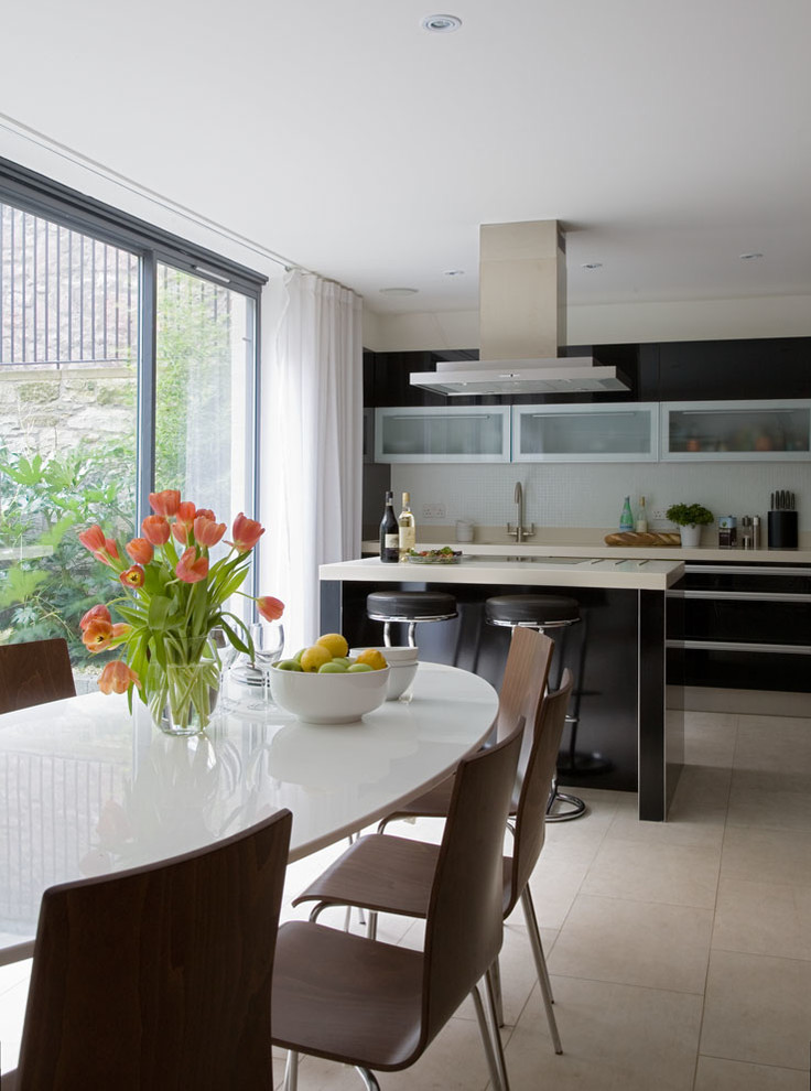 Photo of a medium sized contemporary single-wall kitchen/diner in Edinburgh with flat-panel cabinets, black cabinets, composite countertops, white splashback, ceramic splashback, stainless steel appliances, porcelain flooring and an island.