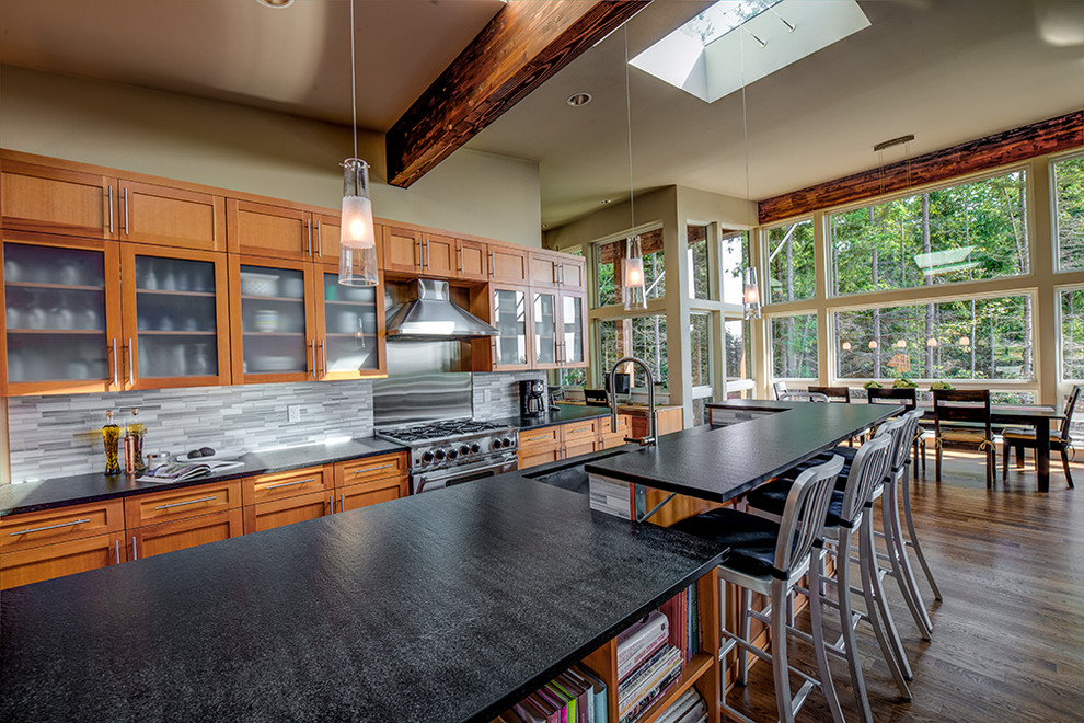 Moderne Küche mit Schrankfronten im Shaker-Stil, hellbraunen Holzschränken, Granit-Arbeitsplatte, Küchenrückwand in Grau, Rückwand aus Steinfliesen, Küchengeräten aus Edelstahl, braunem Holzboden und Kücheninsel in Seattle