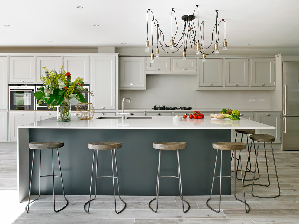 Design ideas for an expansive traditional kitchen/diner in London with a double-bowl sink, shaker cabinets, grey cabinets, stainless steel appliances, an island, grey splashback and glass sheet splashback.