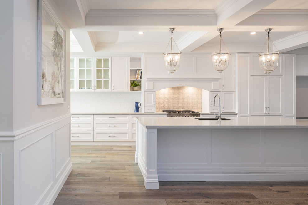 Idéer för att renovera ett stort maritimt vit vitt kök, med en undermonterad diskho, skåp i shakerstil, vita skåp, marmorbänkskiva, vitt stänkskydd, stänkskydd i marmor, rostfria vitvaror, mellanmörkt trägolv, en köksö och brunt golv