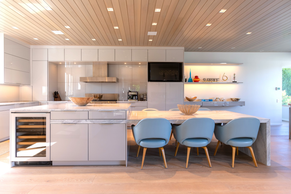 Moderne Küche in L-Form mit flächenbündigen Schrankfronten, grauen Schränken, Küchenrückwand in Grau, Küchengeräten aus Edelstahl, hellem Holzboden, Kücheninsel, beigem Boden und grauer Arbeitsplatte in New York