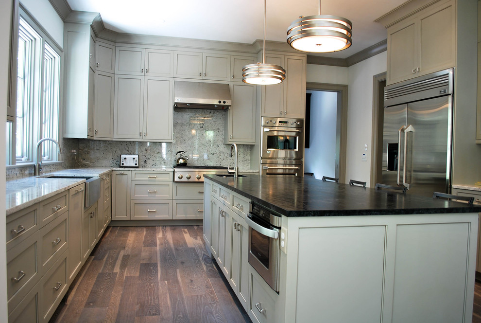 Kitchen - coastal medium tone wood floor kitchen idea in Charleston with a farmhouse sink, shaker cabinets, gray cabinets, granite countertops, gray backsplash, stainless steel appliances and an island