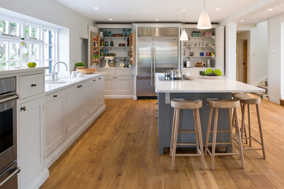 Geschlossene, Mittelgroße Klassische Küchenbar in L-Form mit Schrankfronten im Shaker-Stil, hellem Holzboden, Kücheninsel und braunem Boden in Surrey